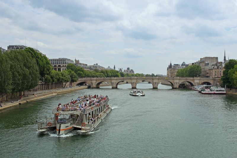 An image of a cozy Seine River cruise, showcasing passengers enjoying the sights of Paris' landmarks from the water