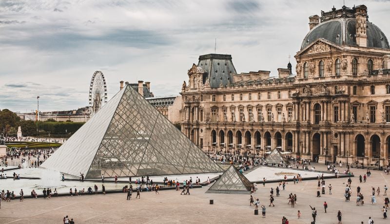 The Louvre Museum exterior with its glass pyramid entrance, surrounded by historic architecture