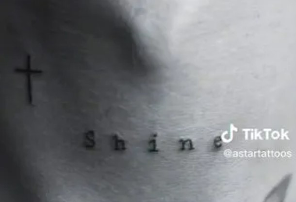 A cross and the word 'Shine' appear on the back of his neck