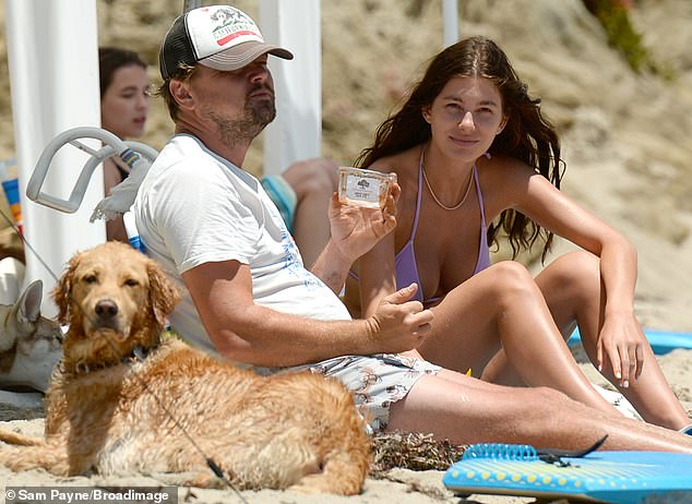 Beach bum chic: The 45-year-old wore a white printed t-shirt with a printed bathing suit, as he sat in a low lounge chair, next to Morrone, 23